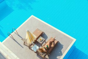 A woman sunbathing beside a clear blue pool, enjoying a summer day.