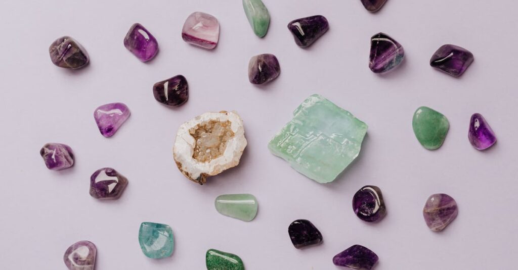 Flat lay of assorted polished gemstones including amethyst and jade on a light background.